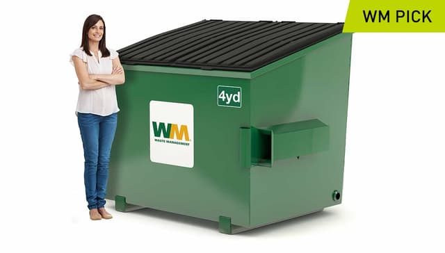 Woman stands next to a 4-yard dumpster- Waste Management’s pick in terms of size.