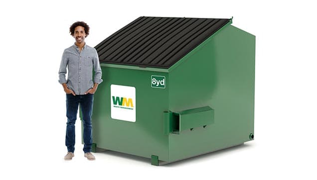 Man stands next to an 8-yard dumpster from Waste Management to show the comparison in height.