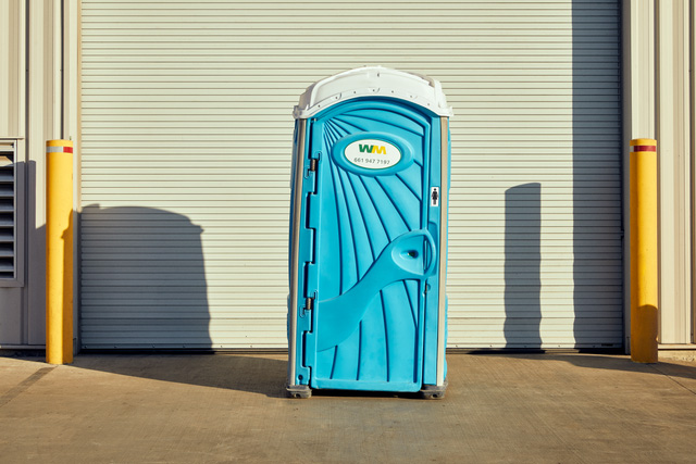 Blue single-stall standalone portable toilet with WM logo on door