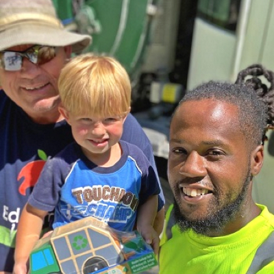 Young male sanitation worker with short hair and beard visiting with child and his older relative