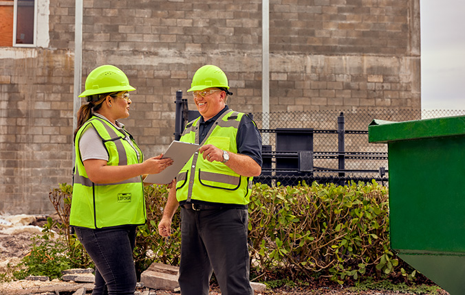 WM representative and client talk outside while wearing hard hats and safety vests